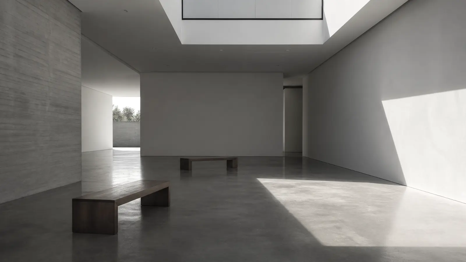 An empty museum gallery before opening hours, polished concrete floor catching soft morning light from a single skylight.